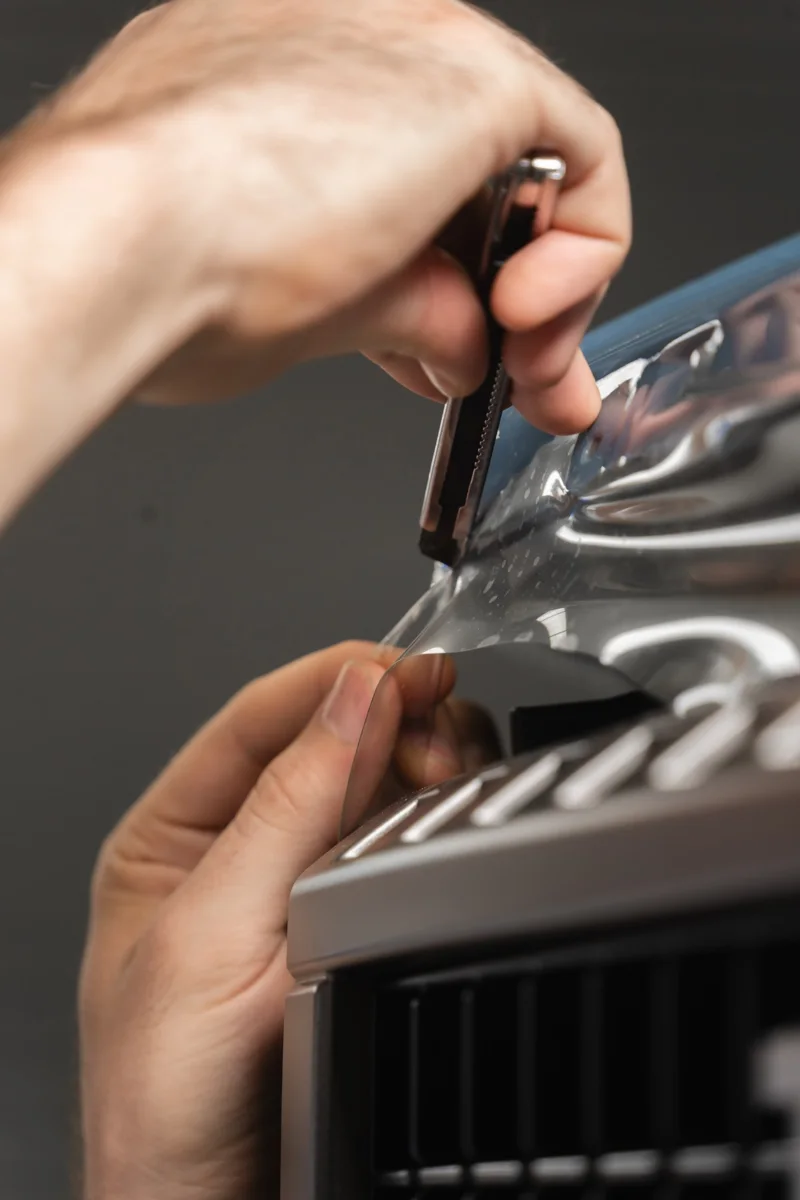 Film being trimmed by hand around a grille